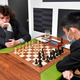 Hans Niemann sits on the left side of a chess board looking down with concentration